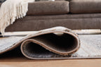 Gray rug corner with visible rounded edge binding and short pile