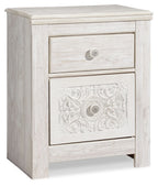 Whitewashed two-drawer night stand with upper drawer and ornate lower panel