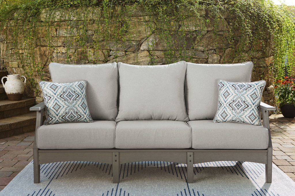 Gray outdoor sofa with three cushions and two geometric patterned pillows on arms