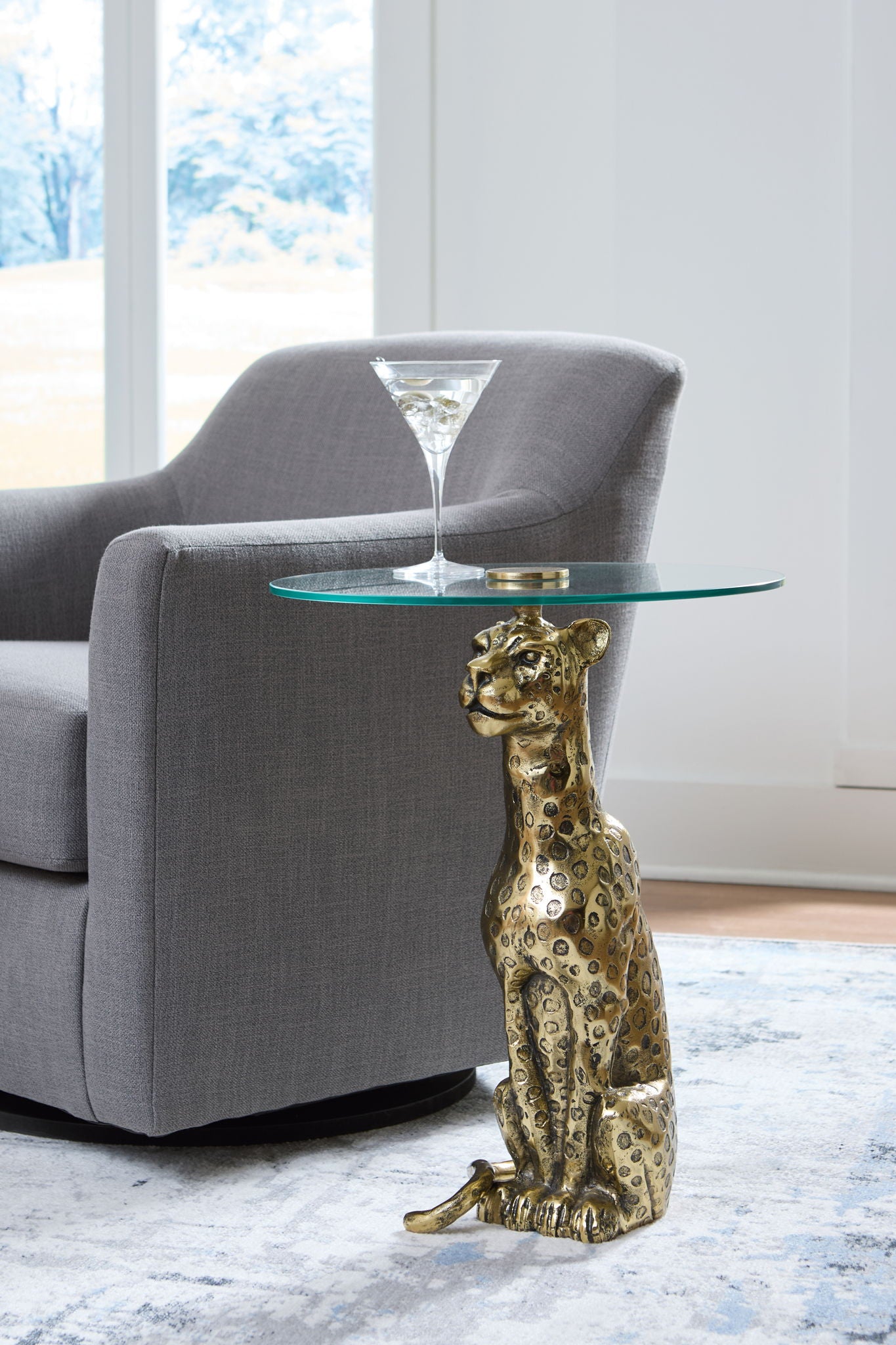 Accent table with round glass top and antique gold animal statue pedestal