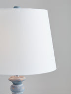 Antique blue table lamp with white fabric shade, close-up of base top