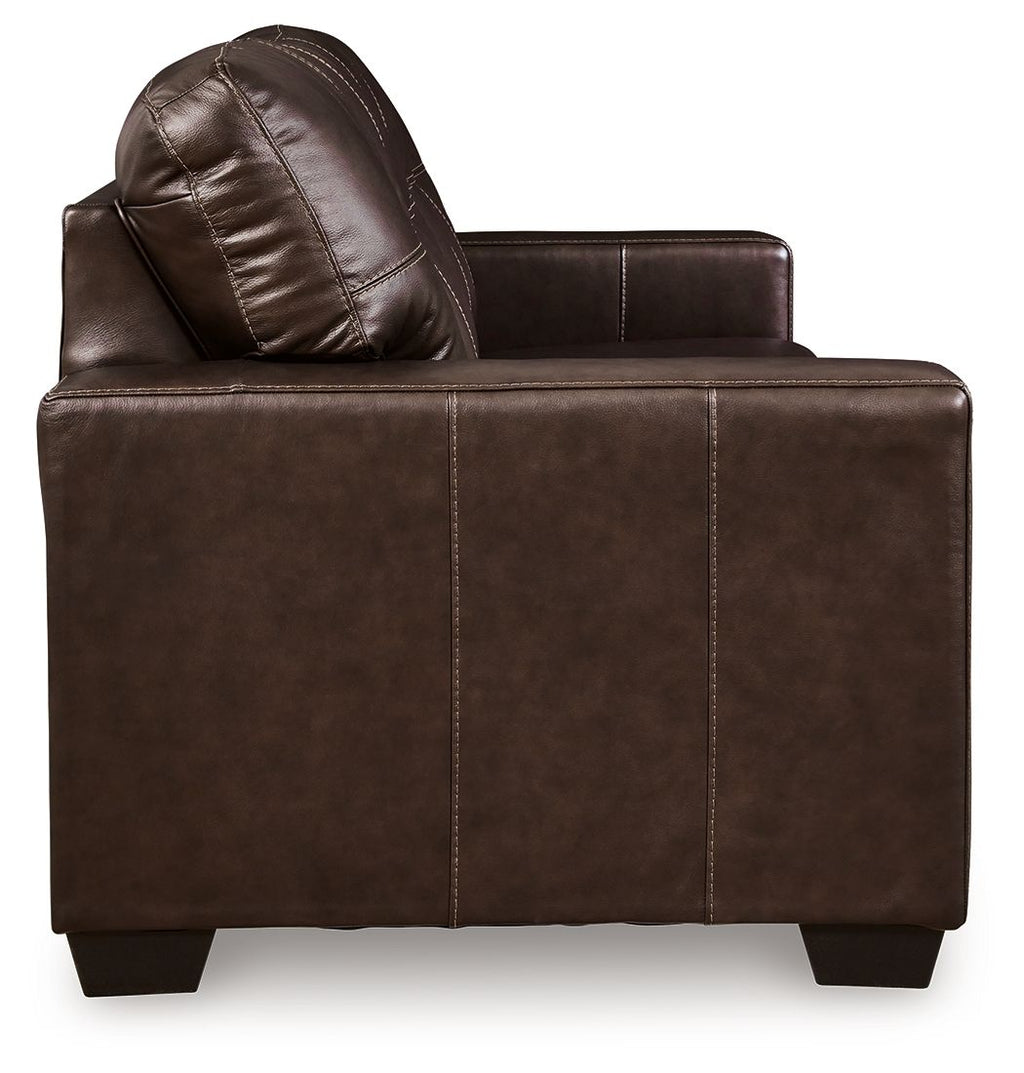 Dark brown leather sofa side view with rolled arm and tufted backrest