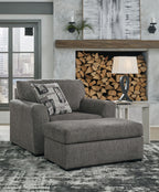 Pewter upholstered chair and a half with patterned pillows, ottoman-style base