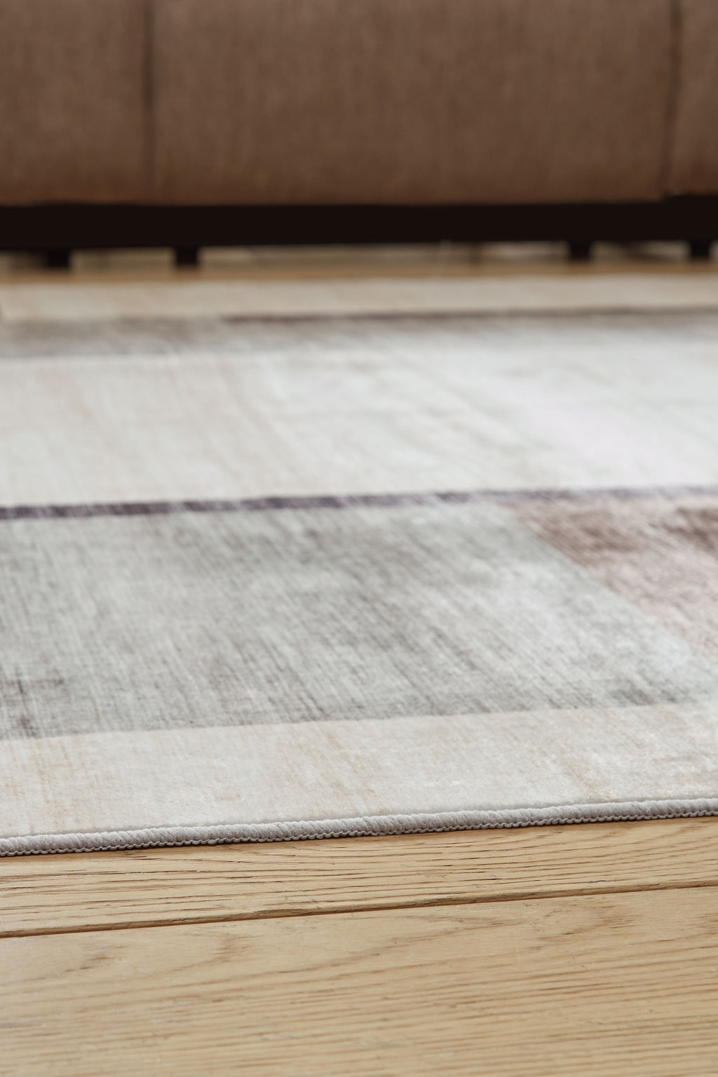 Beige & gray abstract washable rug laid flat with stitched edge trim