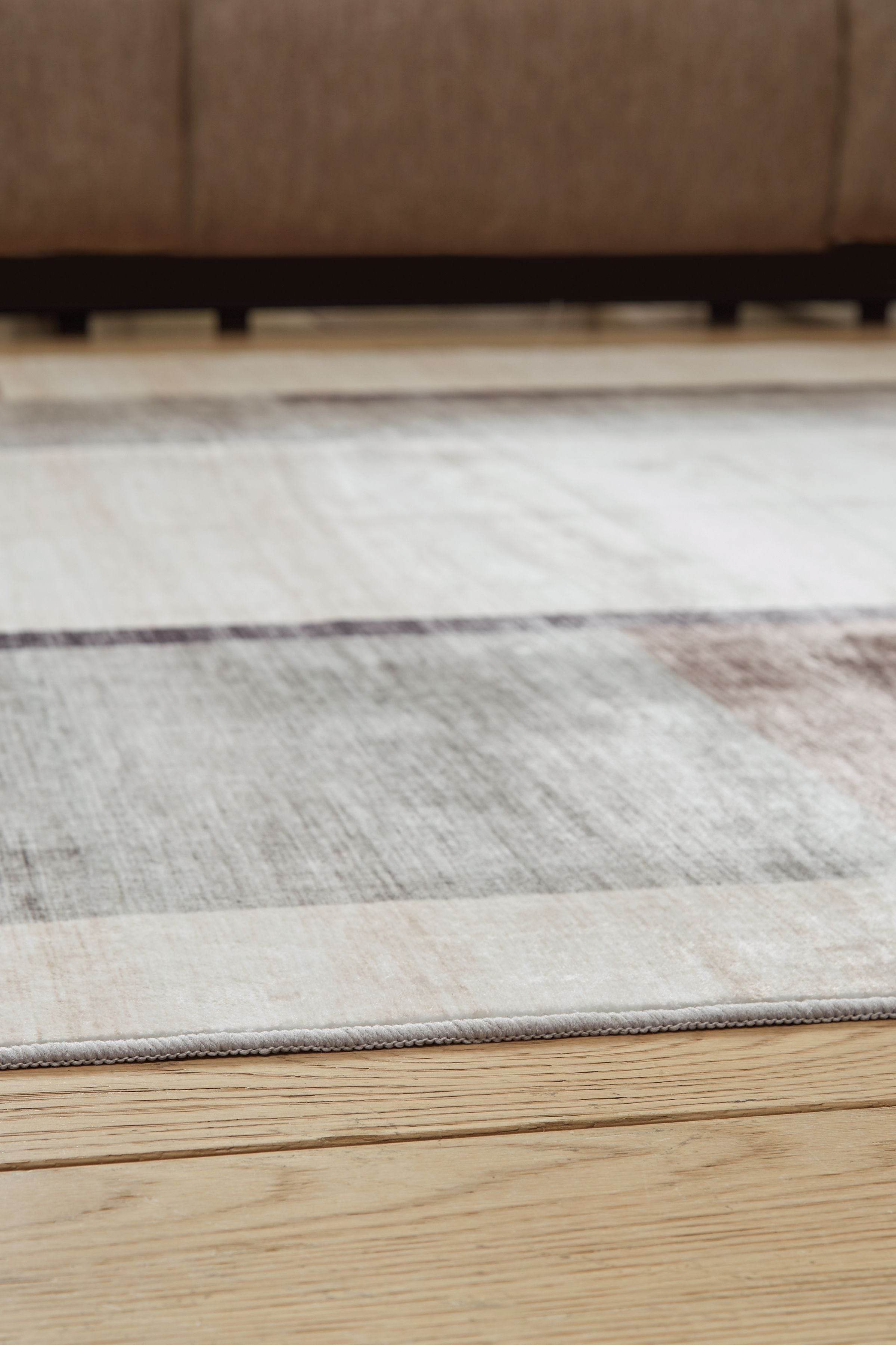 Beige & gray abstract washable rug laid flat with stitched edge trim