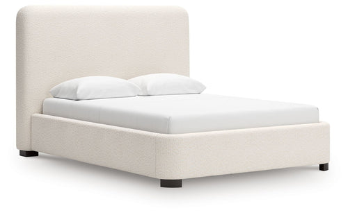 Beige upholstered bed with tall padded headboard and low block legs