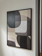 Framed abstract wall art on wall with black and white overlapping oval and rectangle forms.