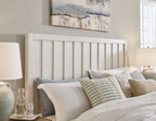 White panel bed headboard with vertical slats and rounded top rail, styled with pillows