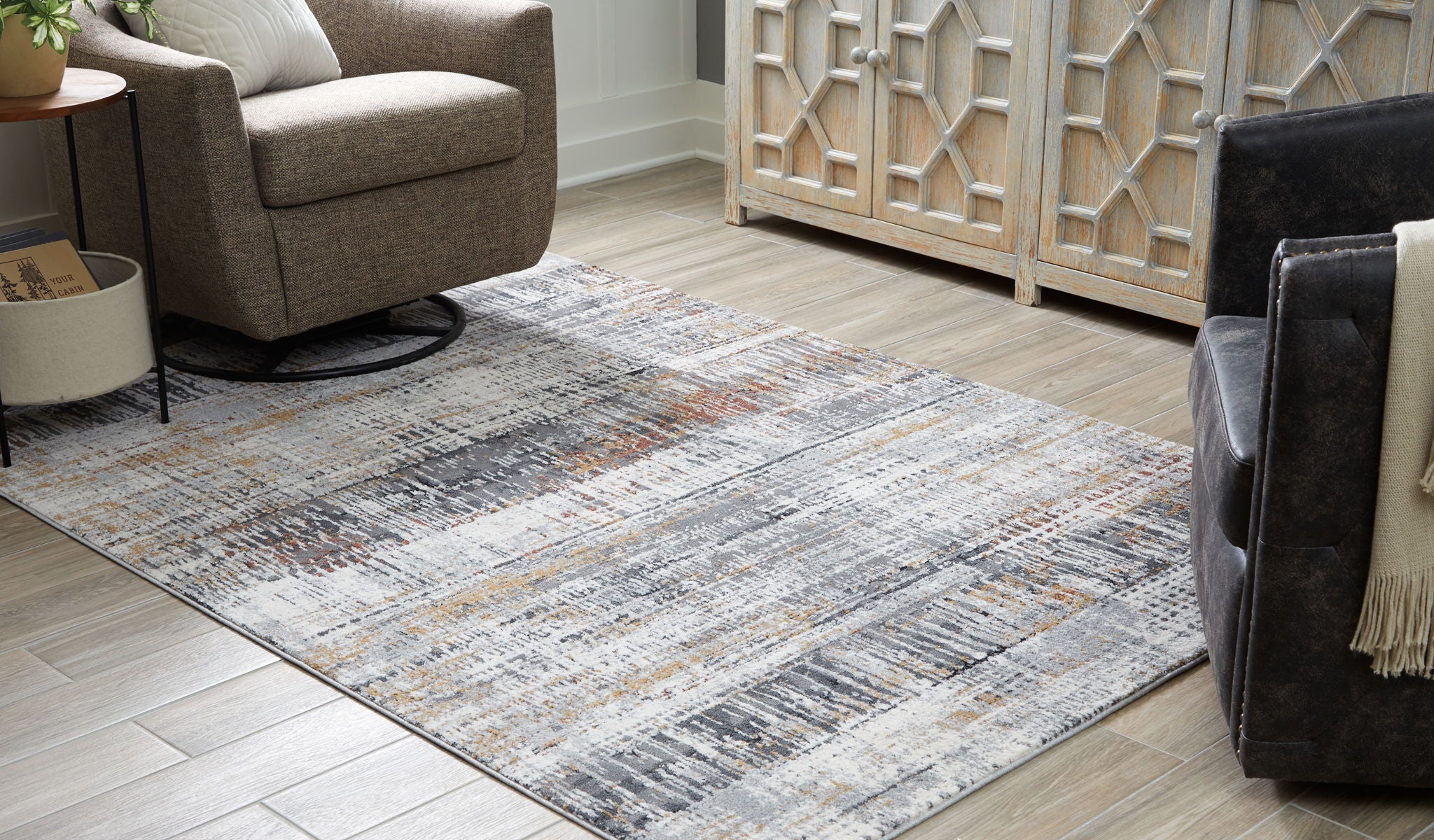 Abstract multi-color area rug on wood floor, gray, white, and muted orange tones