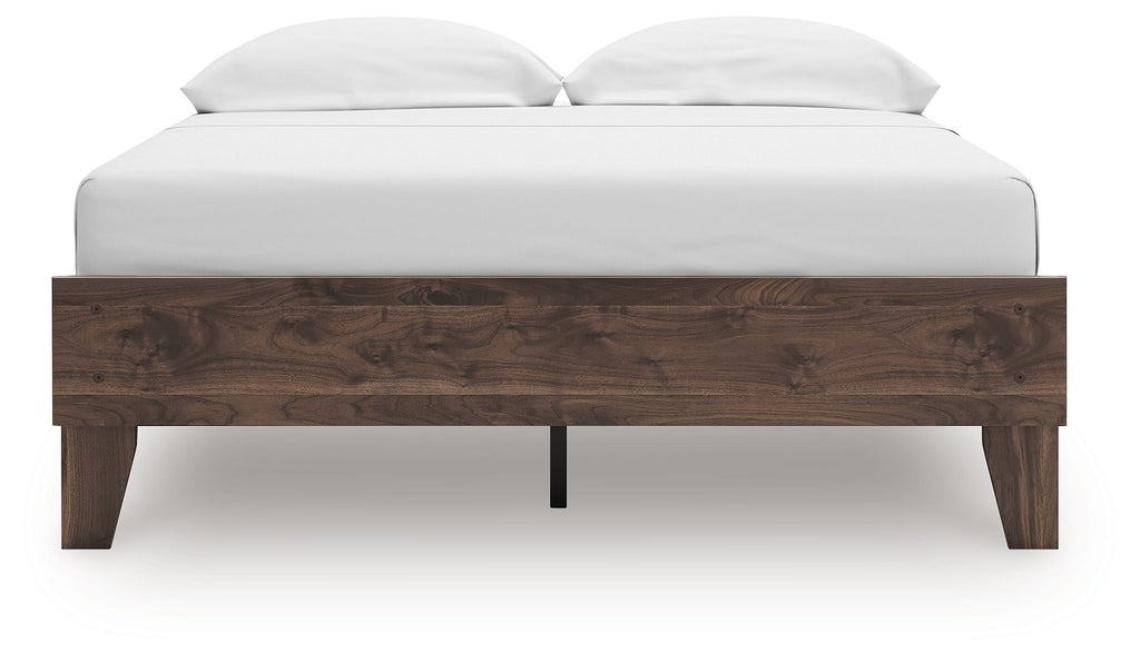 Platform bed with light brown wood headboard and two white pillows