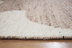 Close-up of beige and white rug pile with mottled fibers and trimmed edge