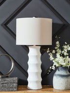White table lamp with drum shade and ridged base, standing on surface