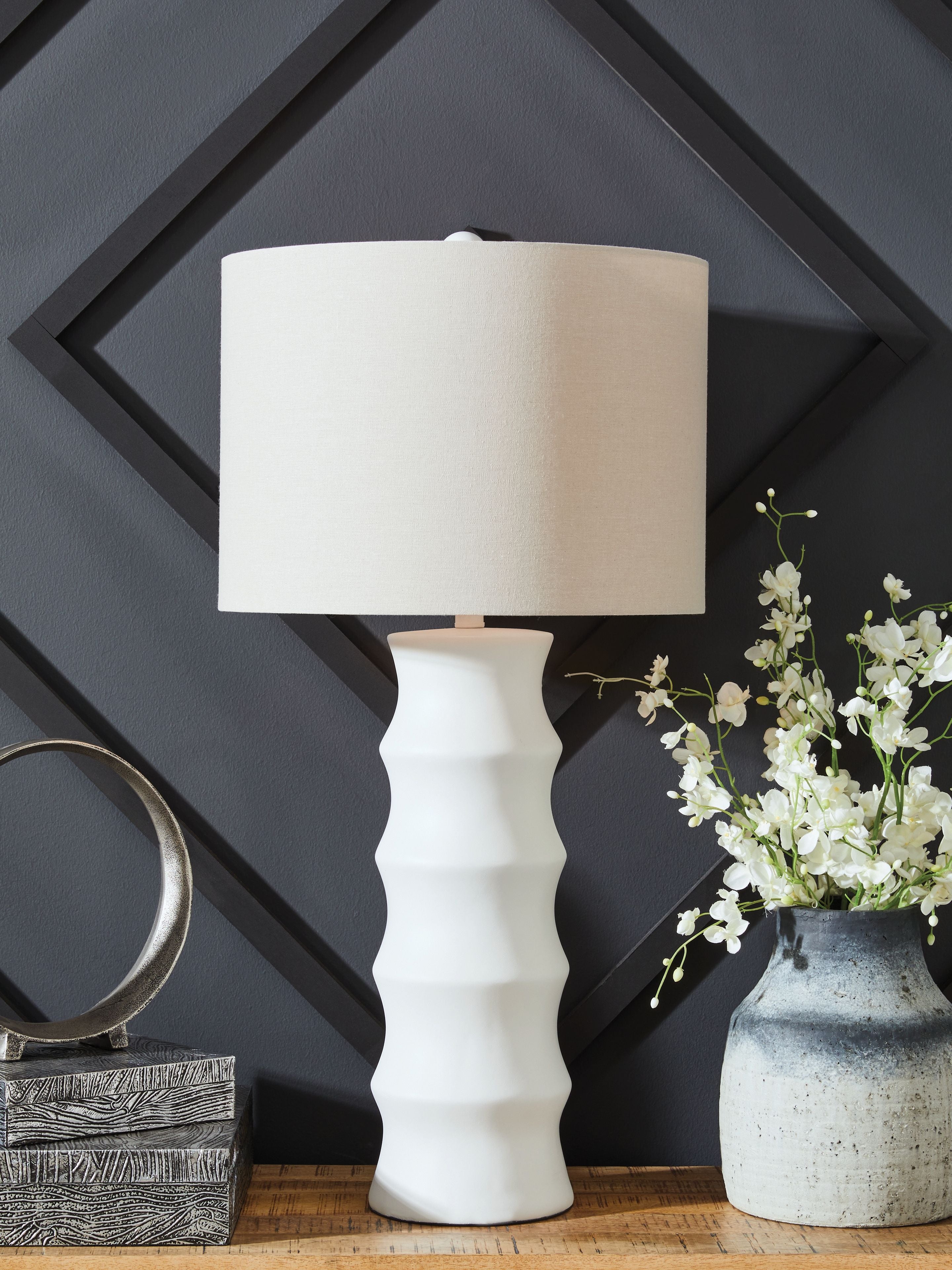 White table lamp with drum shade and ridged base, standing on surface