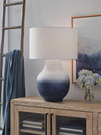 Metal table lamp with white drum shade and speckled navy-to-white base on wood table