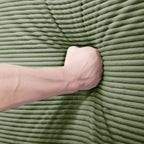 Green corduroy sectional sofa with arm resting on textured seat