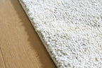 Gray rug edge with textured loop pile and backing fabric visible