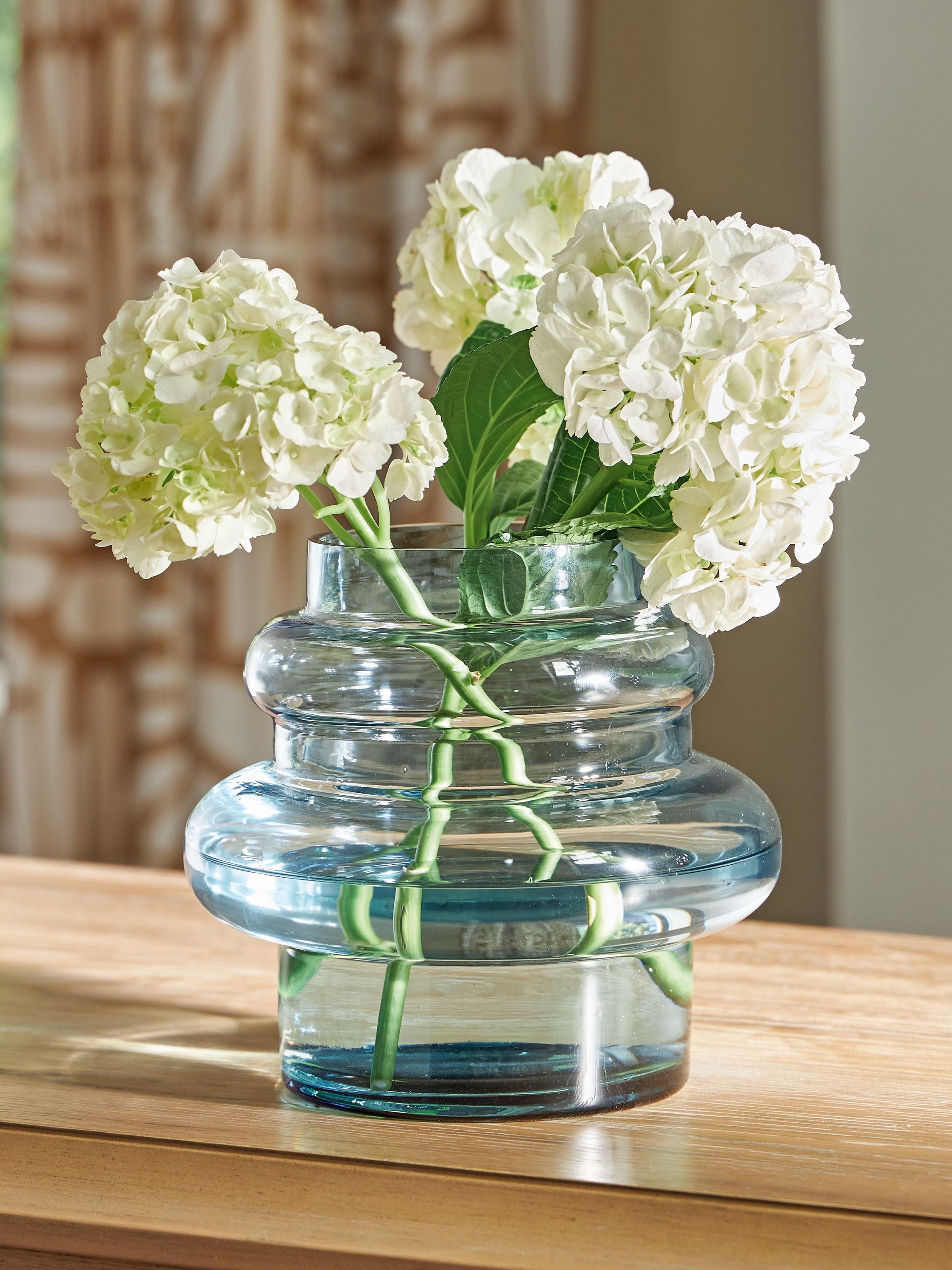 Blue glass vase with clustered white flowers and green stems