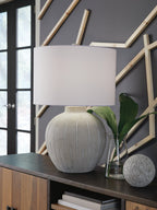 Warm gray poly table lamp with ribbed base and white drum shade, on table