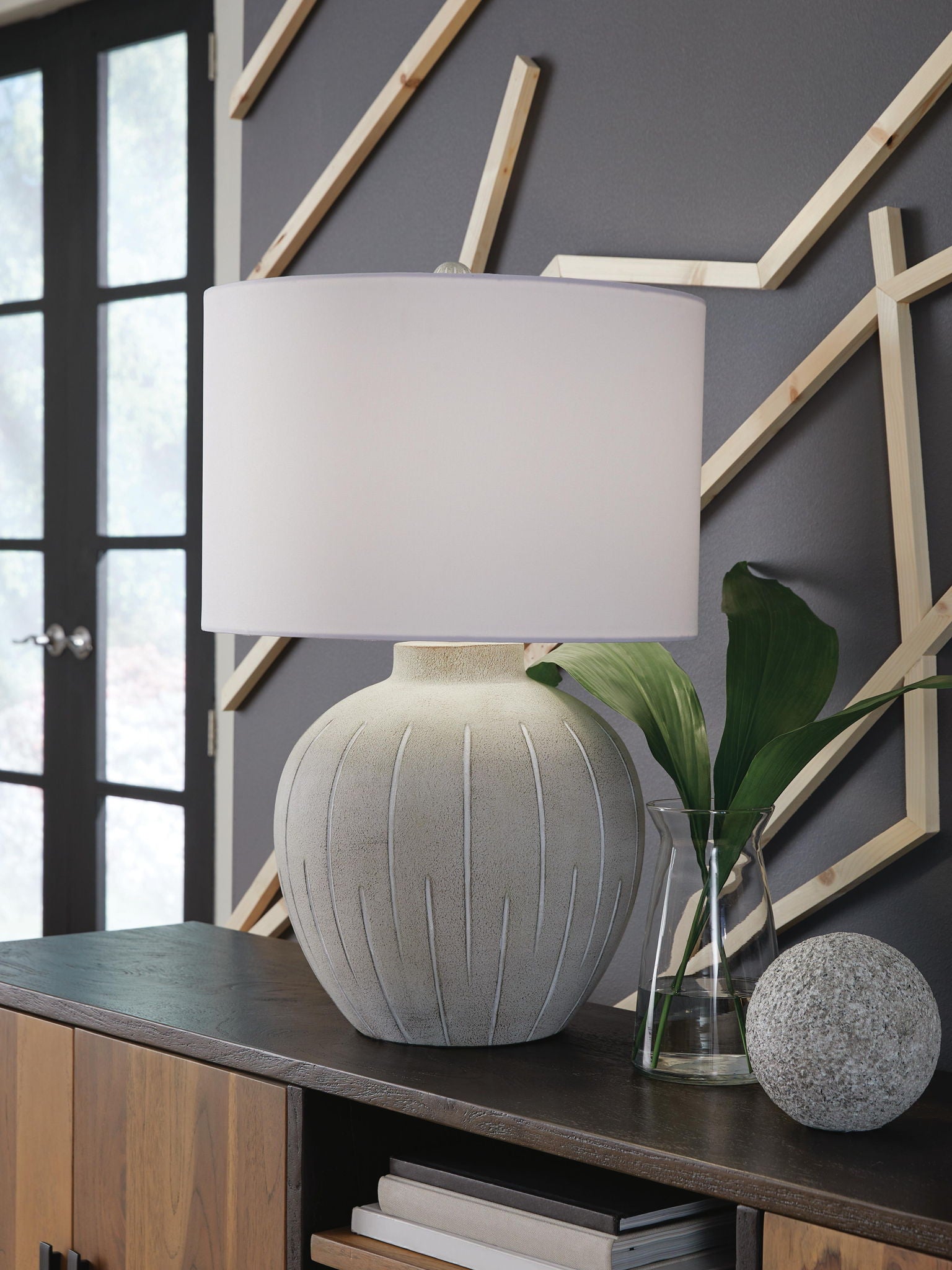 Warm gray poly table lamp with ribbed base and white drum shade, on table