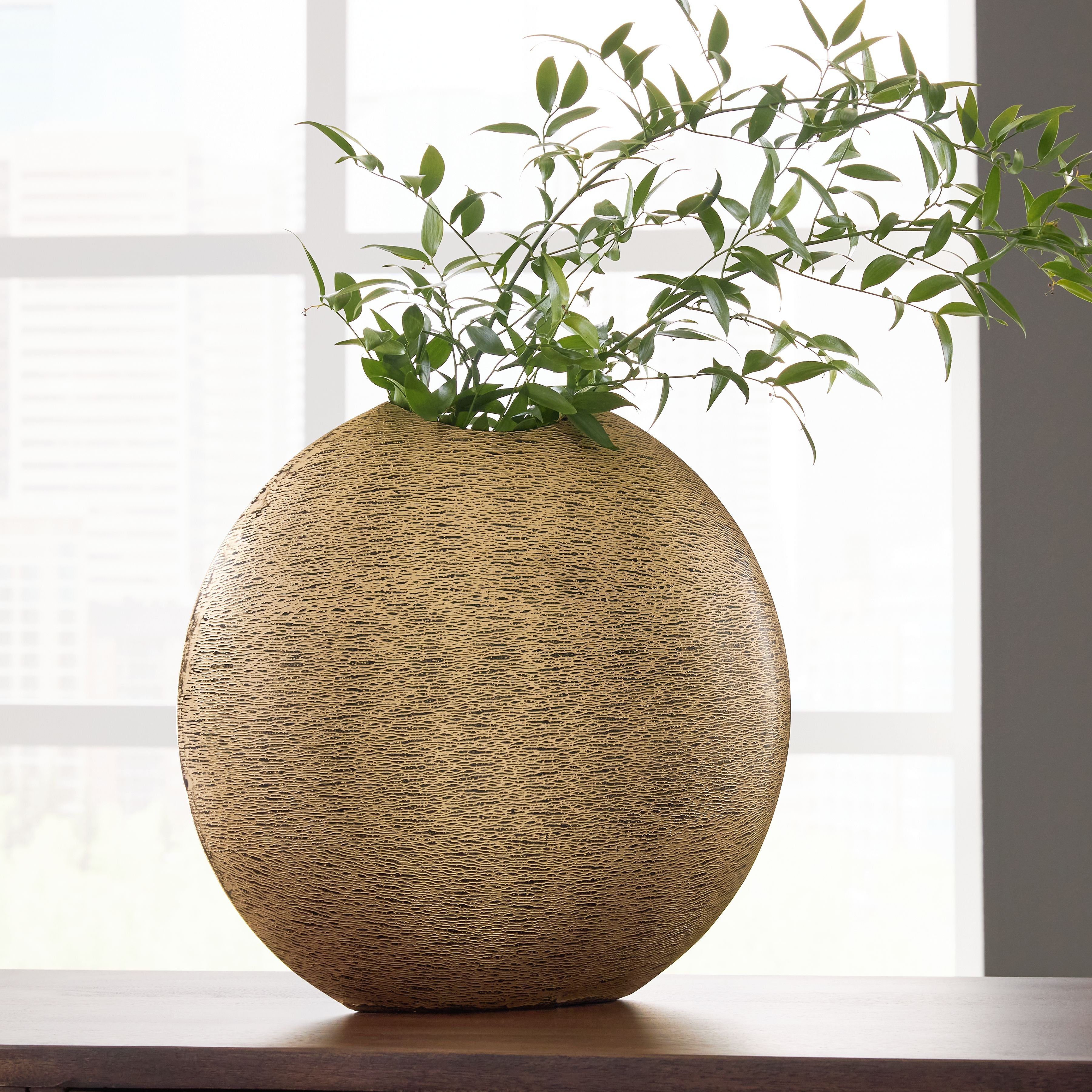 Gold textured vase with rounded teardrop shape and green stems inside
