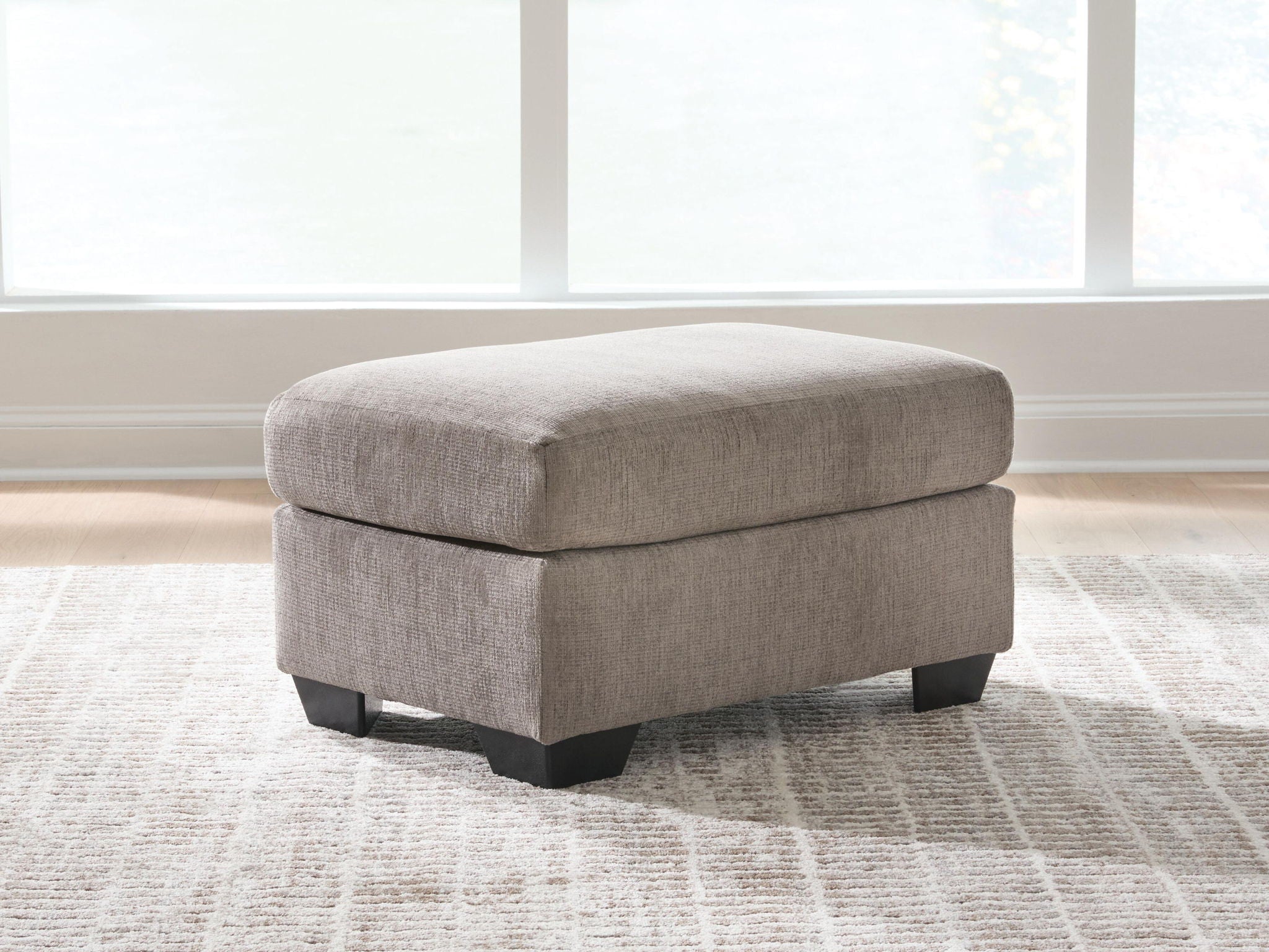 Light gray fabric ottoman with upholstered top and dark block feet