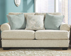 Sandstone loveseat with three cushions: two teal pillows and one light patterned cushion