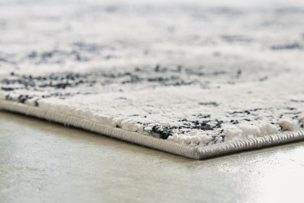 Black and gray rug with textured pile and fringe edge detail