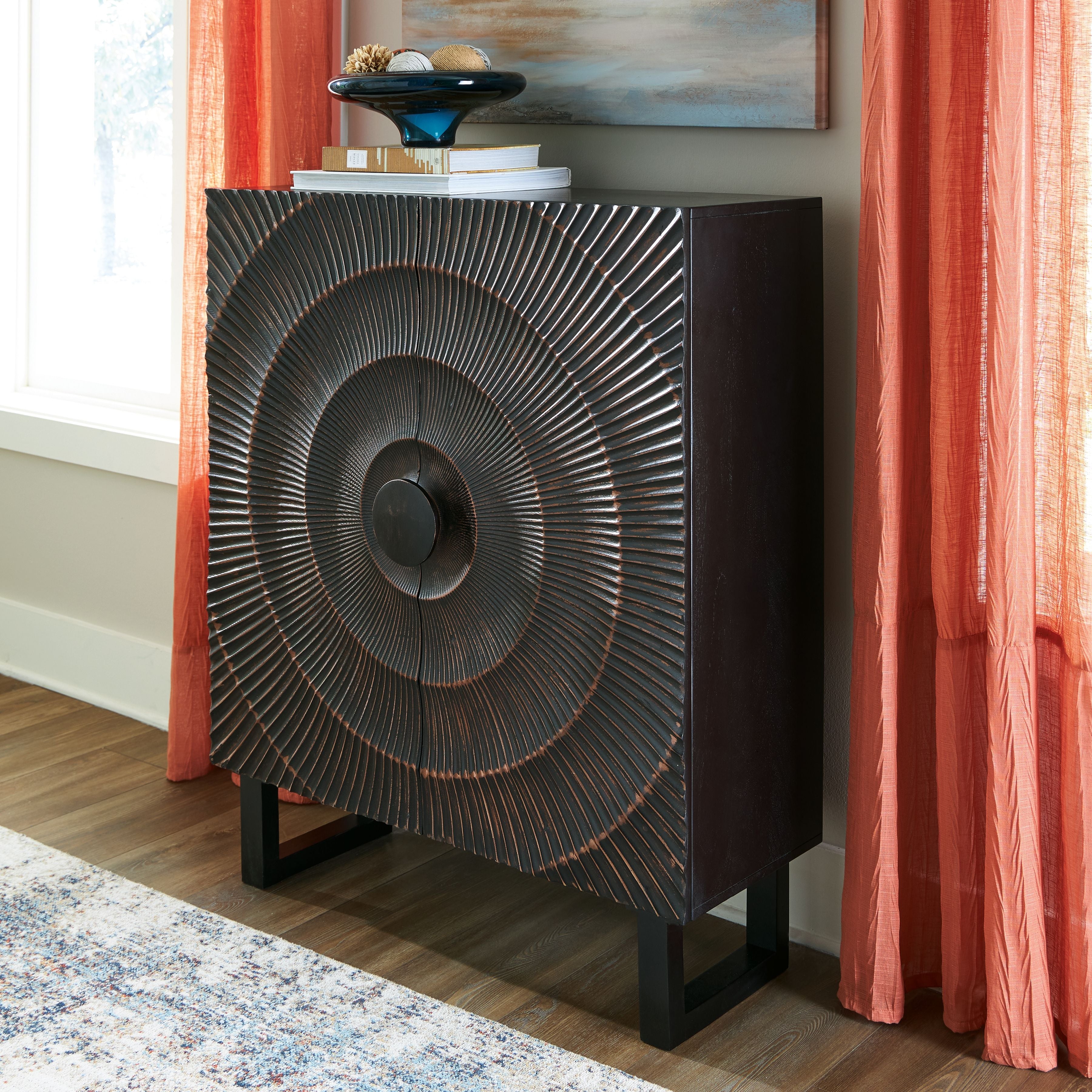 Black accent cabinet with circular radiating metal pattern on the front