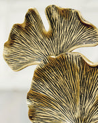 Close-up gold-finish abstract ginkgo leaves sculpture with dark base