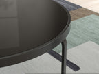 Close-up of black round tabletop edge with curved rim and slender legs
