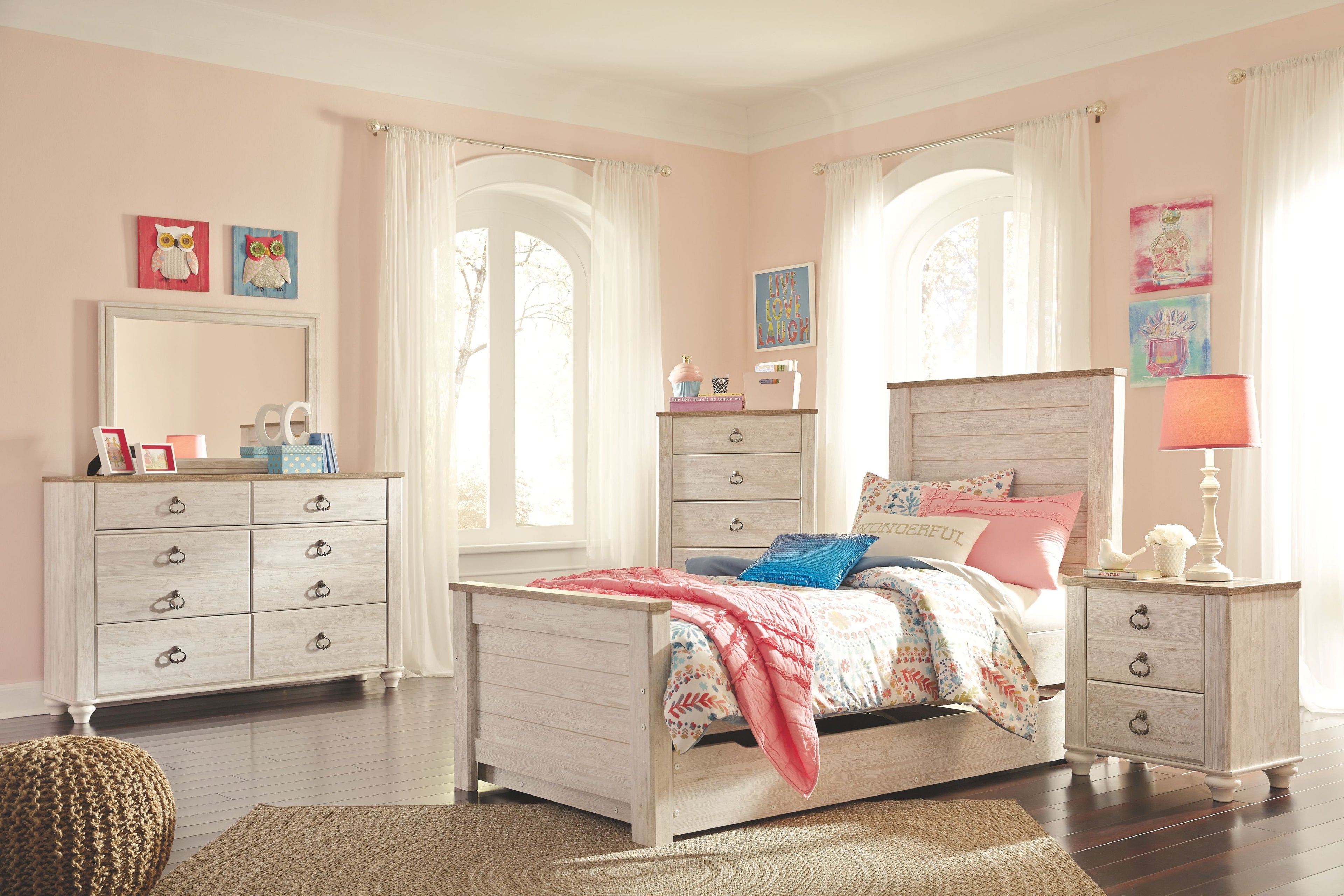 Nightstand with drawers, dark metal pulls, and turned legs beside the bed