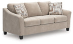 Taupe fabric sofa with three seat cushions and two patterned throw pillows