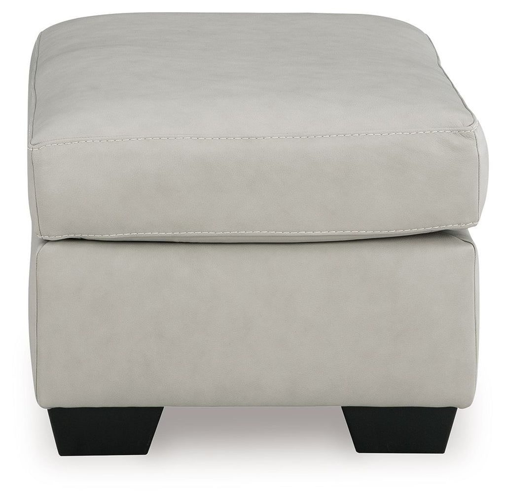 Light beige upholstered ottoman with rounded top corners and dark block feet