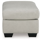 Light beige upholstered ottoman with rounded top corners and dark block feet