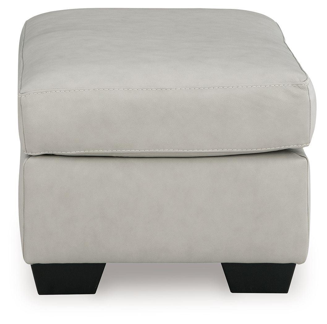 Light beige upholstered ottoman with rounded top corners and dark block feet
