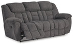 Charcoal gray reclining sofa with extended footrest and tufted back cushions