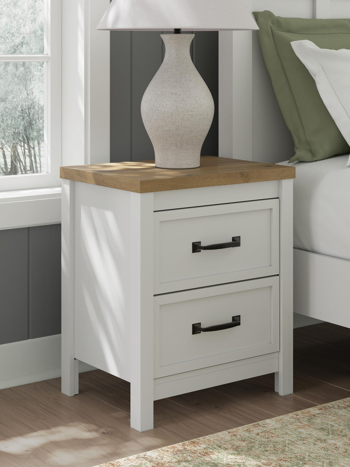 White two-drawer nightstand with brown top and black pulls, styled with a vase