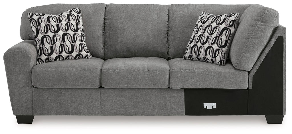 Gray sofa with corner wedge and three back cushions, two patterned pillows