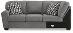 Gray sofa with corner wedge and three back cushions, two patterned pillows
