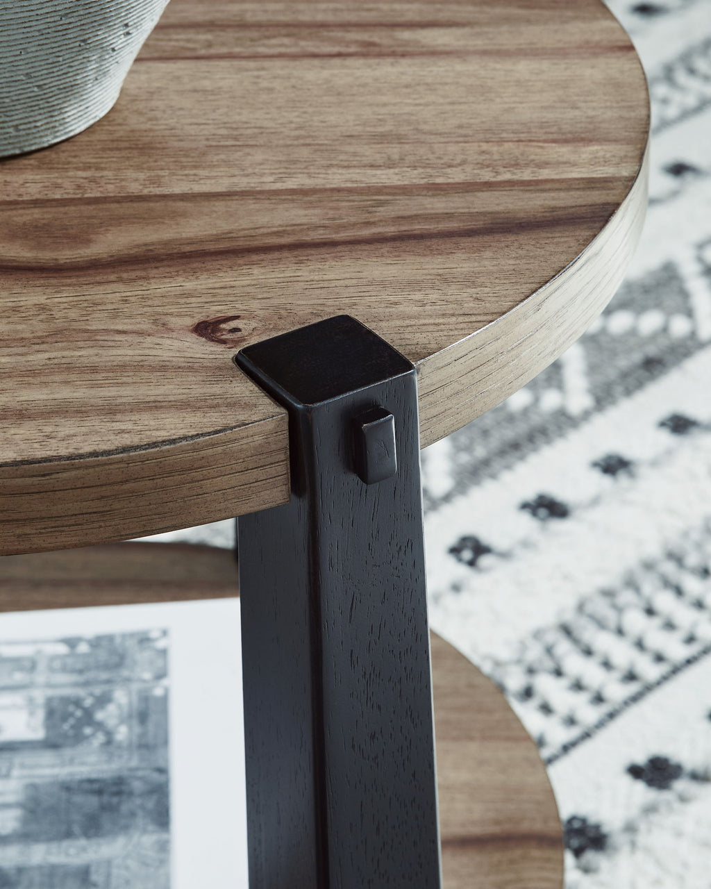 Close-up of dark corner cap and light wood edge on a round two-tier table.