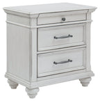 Whitewashed three-drawer nightstand with metal handles and turned legs