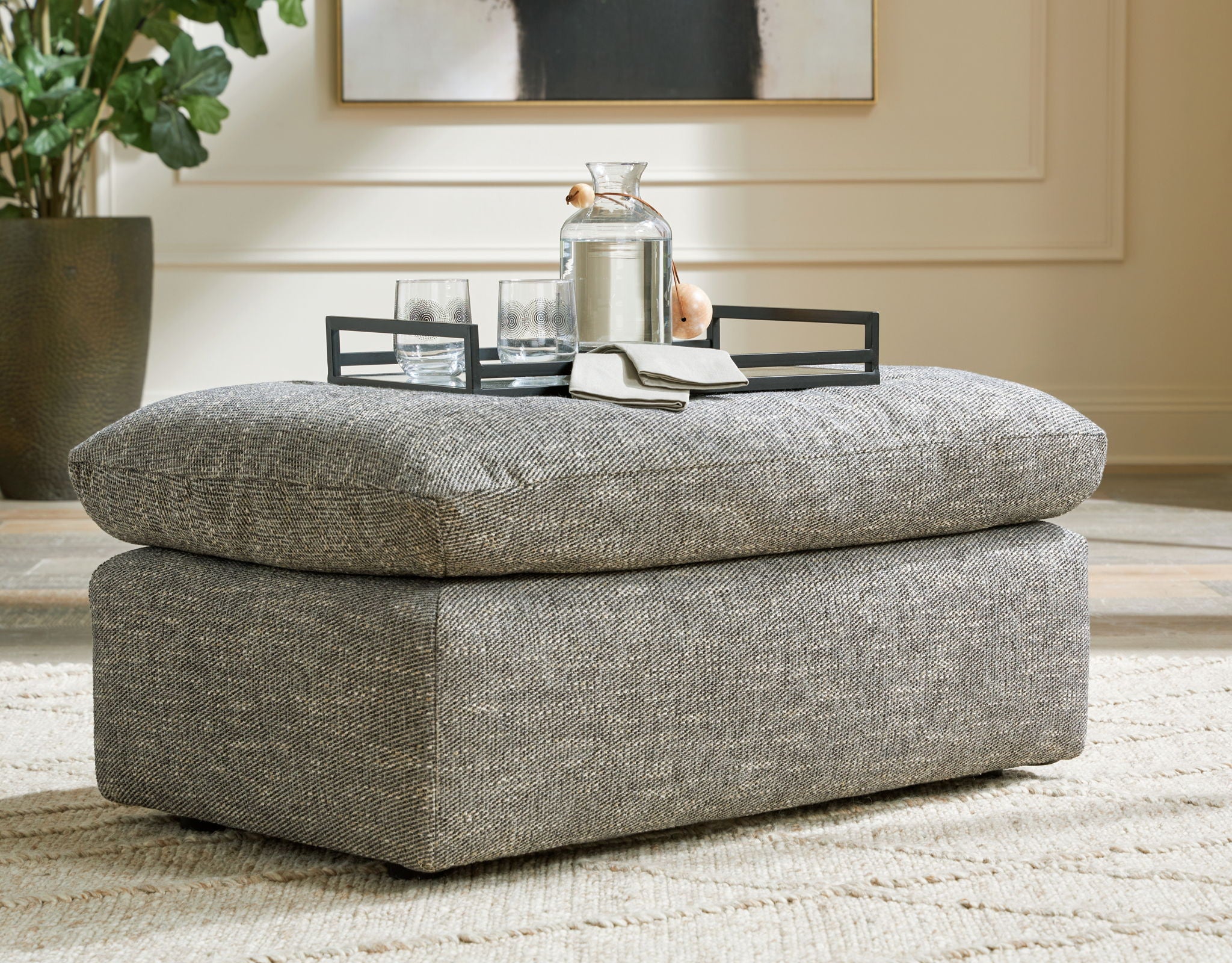 Gray ottoman with textured fabric top and thick upholstered base