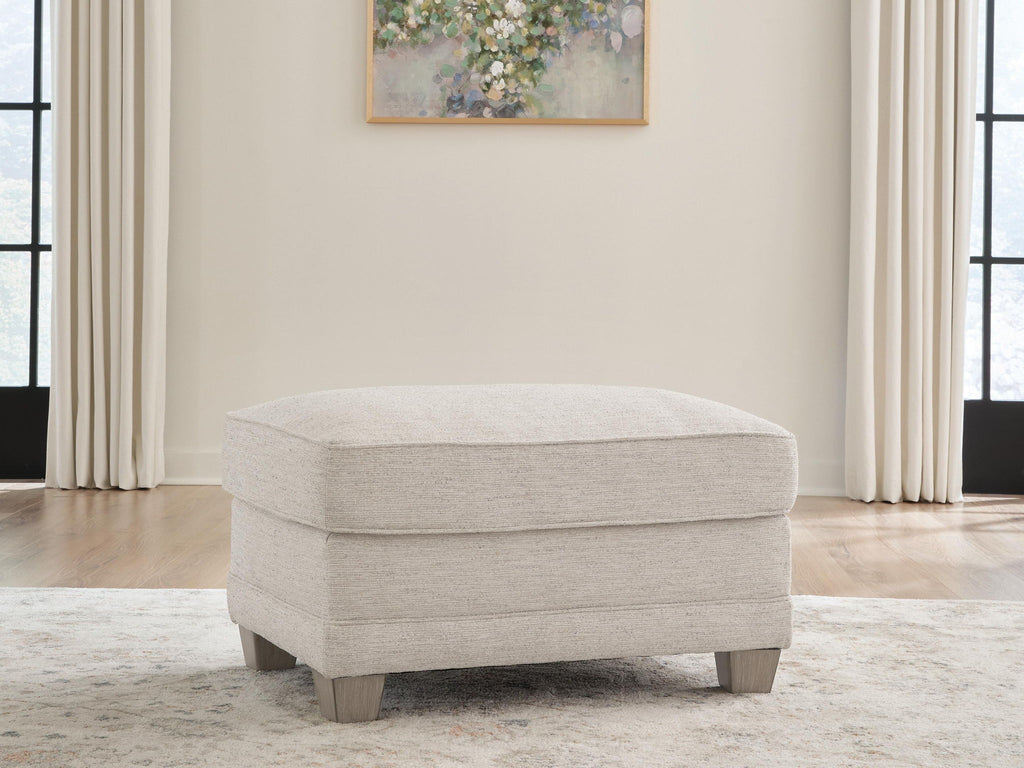 Opal fabric ottoman in front view with domed top and wooden feet