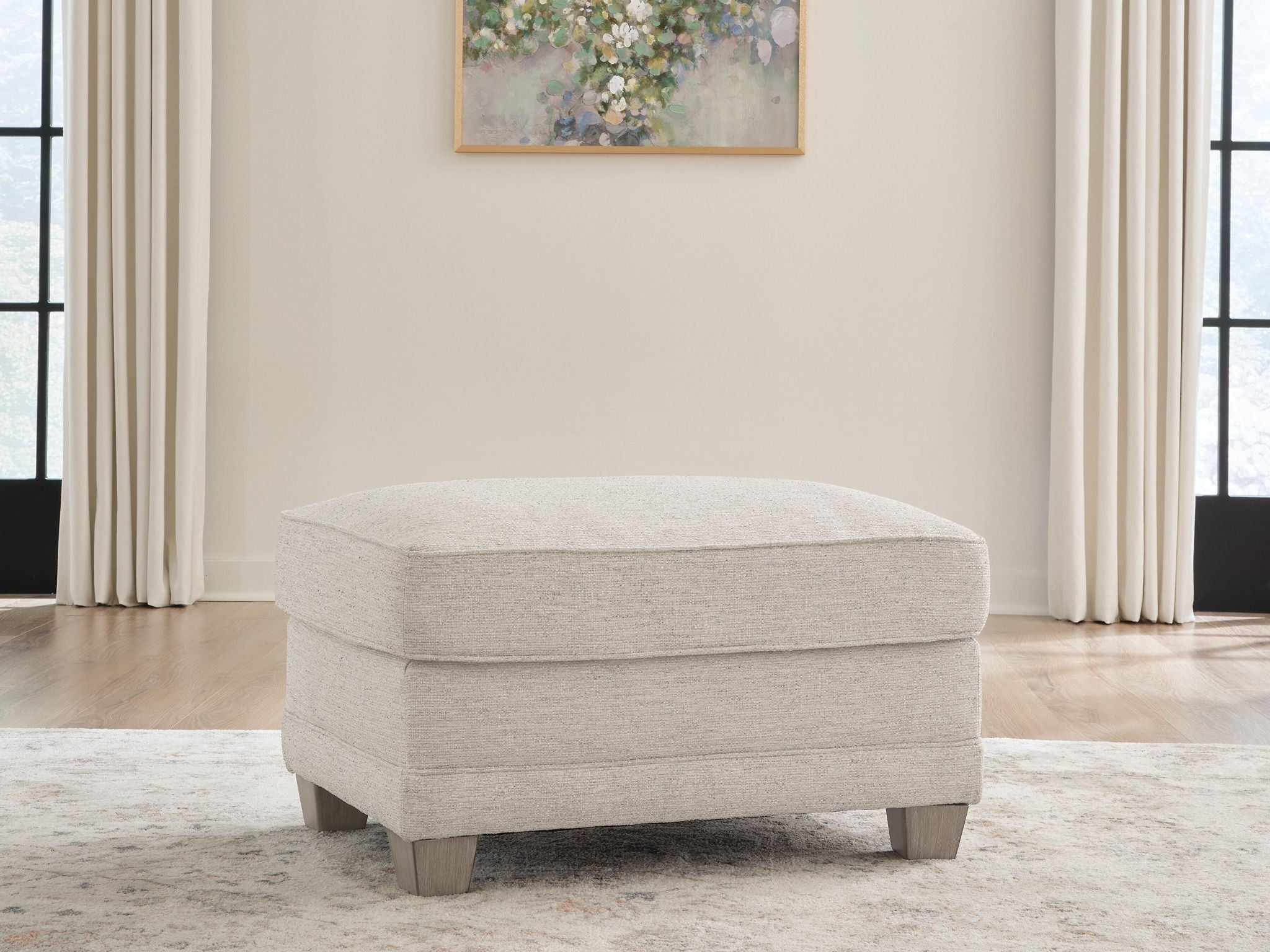 Opal fabric ottoman in front view with domed top and wooden feet