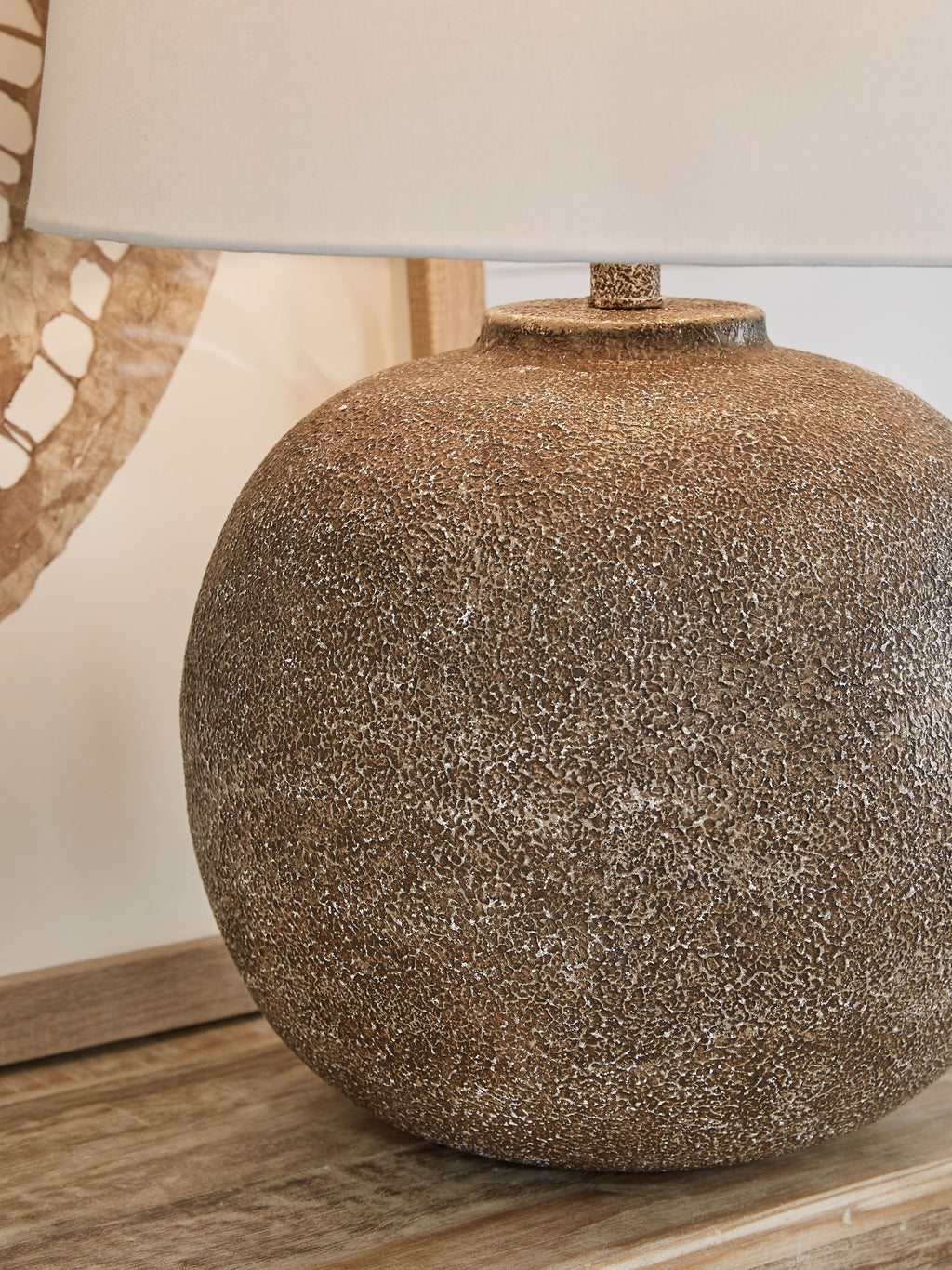 Antique brown metal table lamp close-up with speckled globe base and white shade