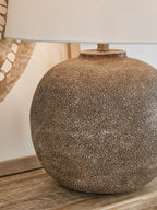Antique brown metal table lamp close-up with speckled globe base and white shade
