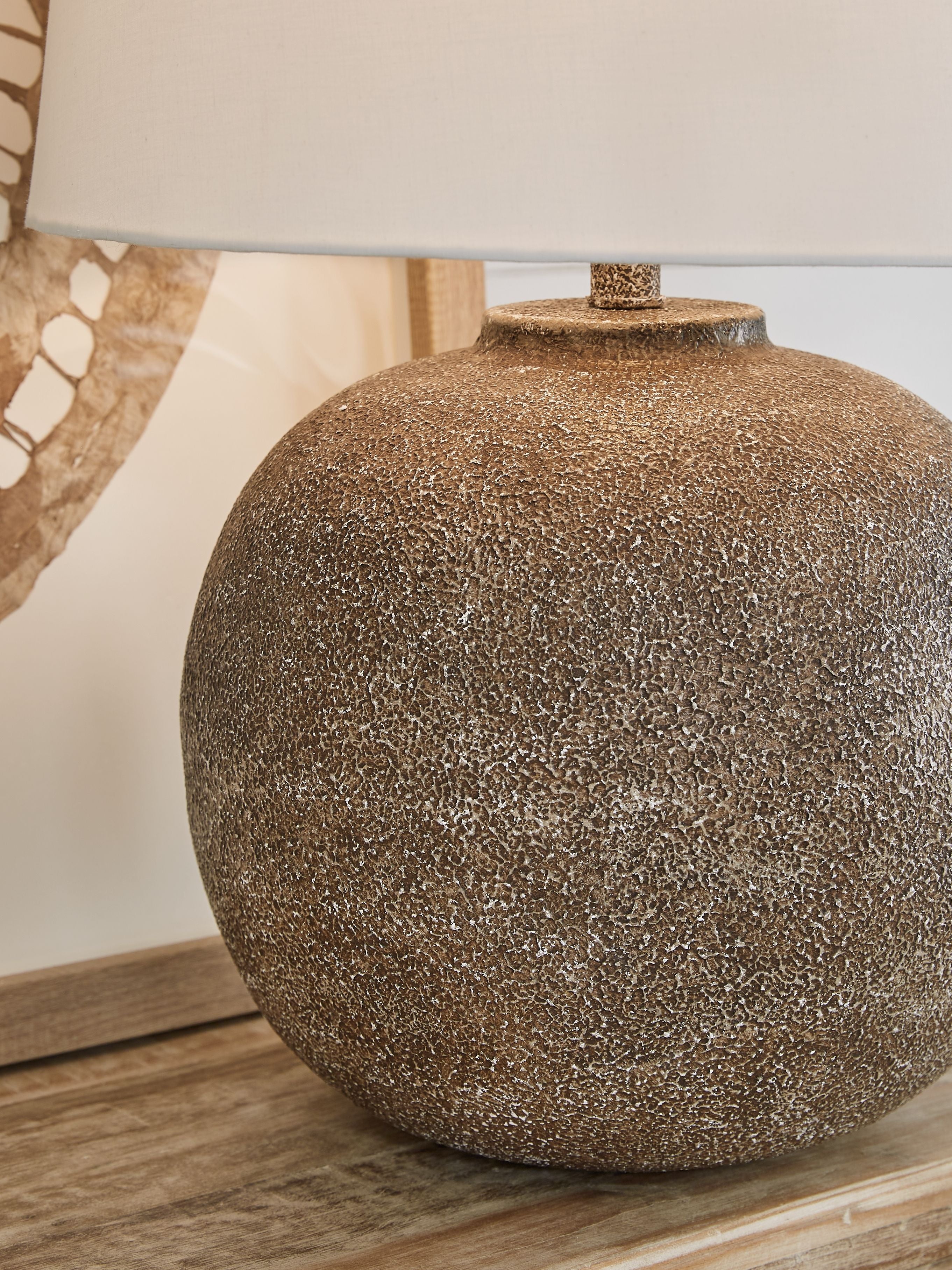 Antique brown metal table lamp close-up with speckled globe base and white shade