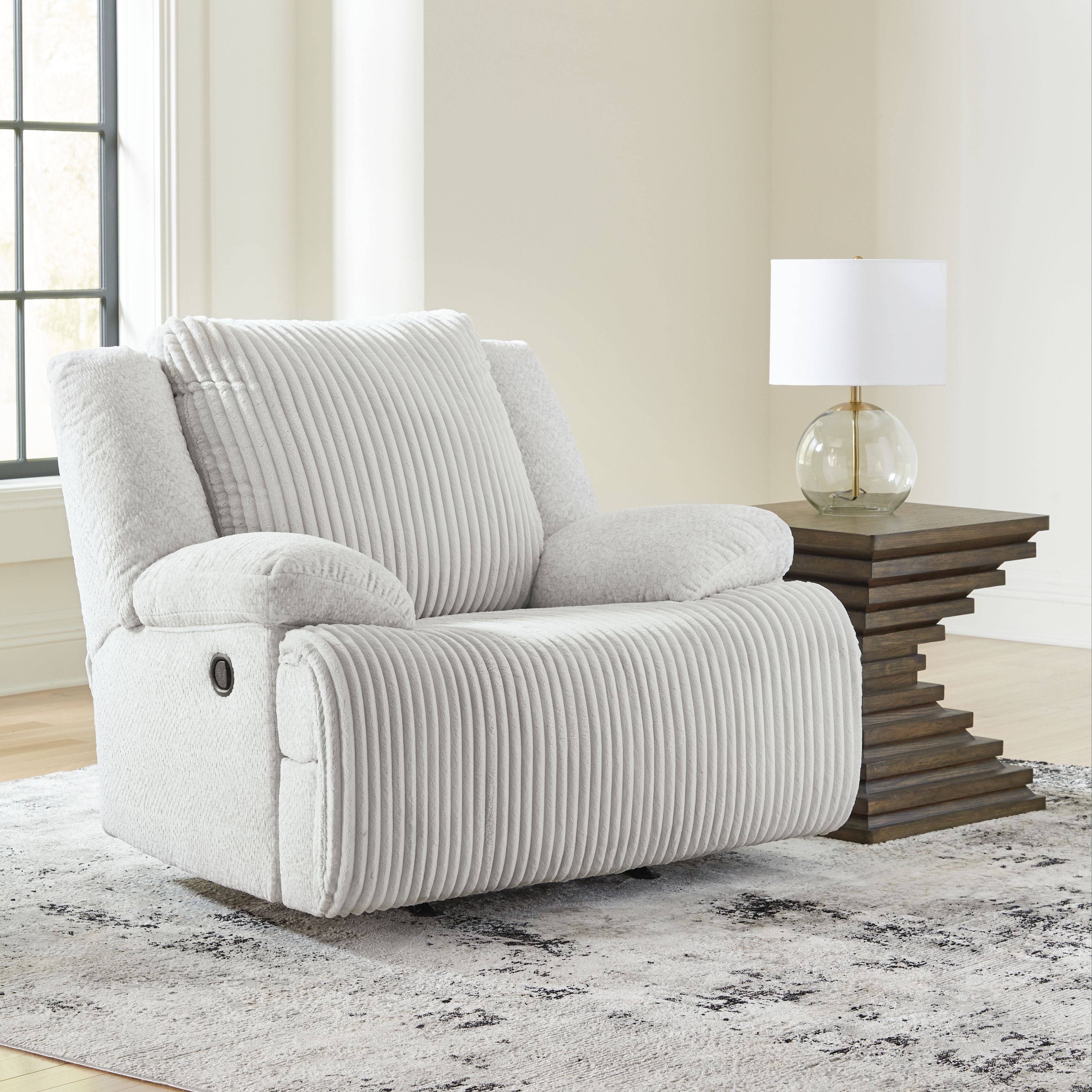 White rocker recliner chair with ribbed upholstery and rounded cushioned arms