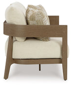 Loveseat side view with dark brown arms, light beige seat cushion and patterned throw pillow