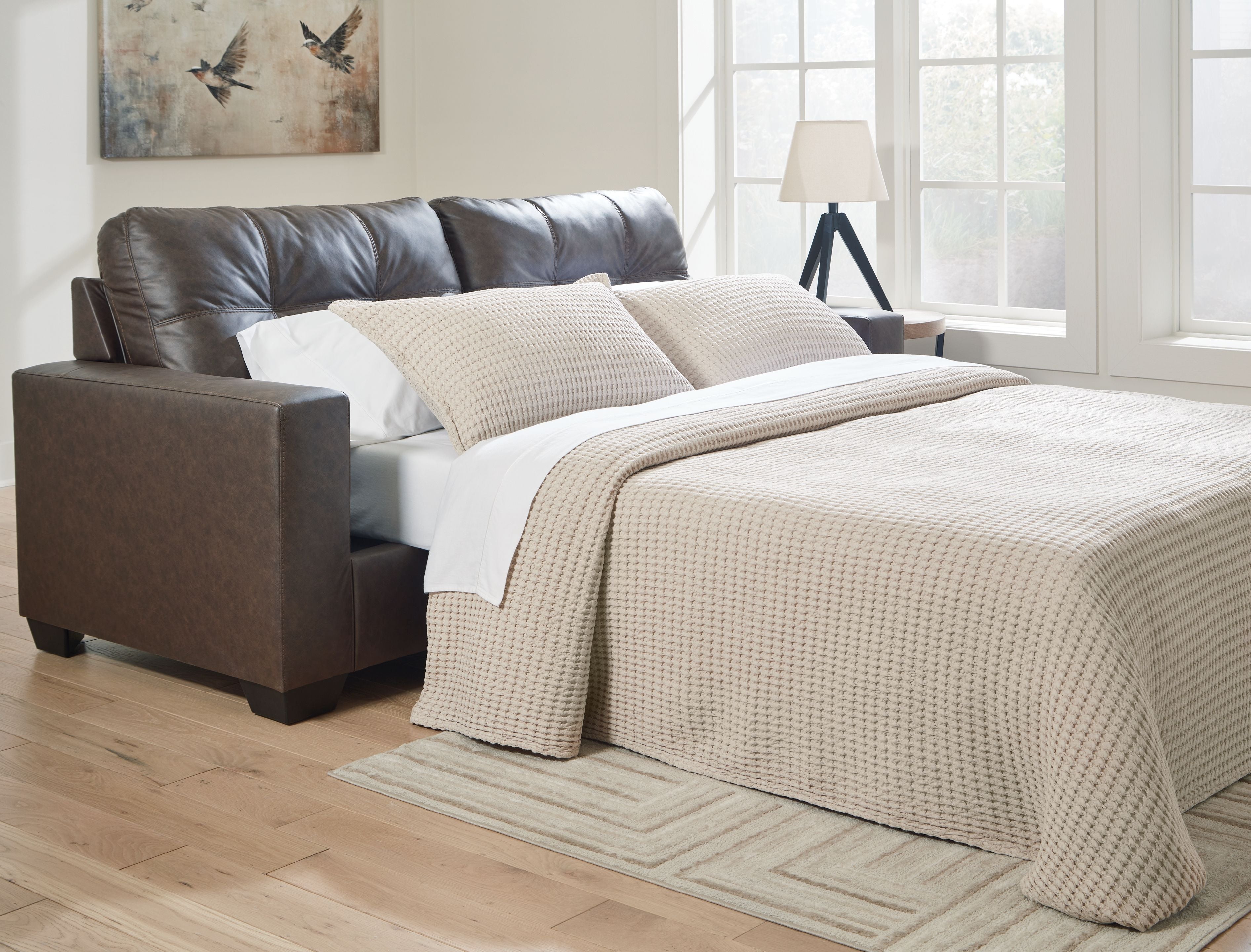 Brown sofa sleeper with tufted back and seat cushions, track arms; shown with white throws.